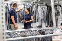 Dois trabalhadores de armazém usando tablet digital para estocar levar roupas em armazém de distribuição — Fotografia de Stock