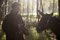 Junger Mann zieht widerwilligen Esel im Wald — Stockfoto