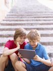 Brüder schauen auf digitales Tablet auf Dorftreppen, Mallorca, Spanien — Stockfoto