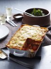 Fresh baked lasagne in dish with missing piece — Stock Photo