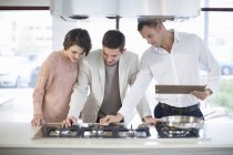 Торговець і середня доросла пара дивиться на холодильник в кухонному шоу-румі — стокове фото