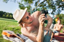 Young man taking photographs at park party — Stock Photo