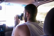 Young man taking photographs through car windscreen — Stock Photo