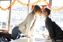 Romântico jovem casal beijando sobre a mesa no café — Fotografia de Stock