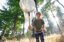 Portrait of boy with butterfly net outdoors — Stock Photo