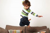 Junge springt auf Sofa — Stockfoto