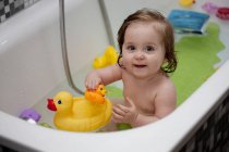 Маленькая девочка в ванной играет с жёлтыми резиновыми утками — стоковое фото