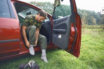 Мужчина, сидящий в машине и надевающий носки — стоковое фото