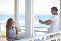 Couple taking photographs on beach house balcony — Stock Photo