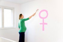 Pregnant woman painting nursery — Stock Photo