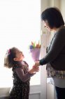 Young girl giving mother flowers — Stock Photo