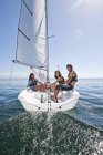 Троє молодих друзів відпочивають на вітрильному човні на воді — стокове фото