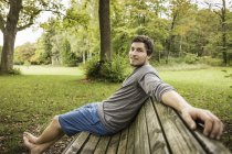 Портрет босоніж молодого чоловіка, що сидить на лавці парку — стокове фото