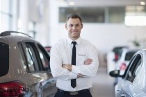 Portrait of smiling salesman in car dealership — Stock Photo
