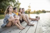 Gruppo di amici seduti sul molo, rilassante — Foto stock