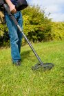 Cropped view of mature man searching grass using metal detector — Stock Photo