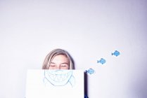 Young woman holding drawing of shark mouth — Stock Photo