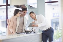 Casal adulto médio e vendedor olhando para tablet digital na sala de exposições da cozinha — Fotografia de Stock