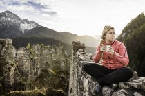 Young woman drinking coffee on top of Ehrenberg castle ruins, Reutte, Tyrol, Austria — Stock Photo