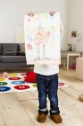 Kleinkind hält Malerei im Wohnzimmer hoch — Stockfoto