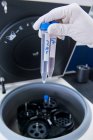 Лаборатория исследования рака, рука ученого-мужчины помещает клетки в центрифугу — стоковое фото