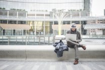 Businessman sitting on wall using laptop — Stock Photo