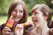2 girls eating popsicles together — Stock Photo