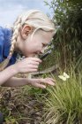 Close up of schoolgirl looking at butterfly in garden — Stock Photo