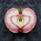 Manzana simétrica mitad con mancha en forma de corazón rojo - foto de stock