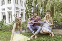Drei Freunde im Garten, Mann spielt Gitarre — Stockfoto
