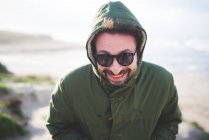 Portrait of mid adult man in hooded jacket at coast — Stock Photo