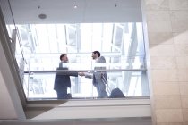 Двоє молодих бізнесменів тремтять руками на балконі конференц-центру — стокове фото
