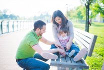 Couple adulte moyen avec fille tout-petit sur banc de parc — Photo de stock