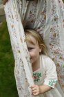 Kleines Mädchen versteckt sich hinter Vorhängen — Stockfoto
