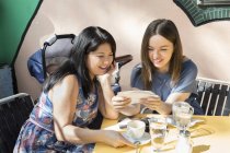 Young woman with mother and baby daughter looking at photographs at sidewalk cafe — Stock Photo