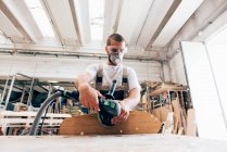 Man sanding skateboard in workshop — Stock Photo