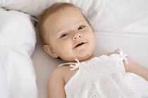 Baby girl lying down and looking at camera — Stock Photo