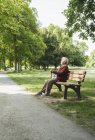 Senior woman sitting on park bench in park — Stock Photo