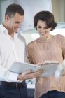 Salesman and female customer looking at brochure in kitchen showroom — Stock Photo