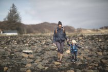 Mother and son holding hands walking on rocks — Stock Photo