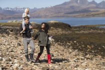 Familia a pie, hombre cargando hijo sobre hombros, Loch Eishort, Isla de Skye, Hébridas, Escocia - foto de stock