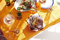 Botellas de comida y cerveza servidas en la mesa a la luz del sol - foto de stock