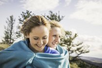 Teenage girl and friend wrapped in turquoise blanket, Bridger, Montana, USA — Stock Photo
