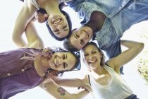 Group of friends in huddle smiling, low angle view — Stock Photo
