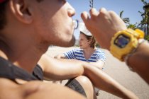 Человек сидит на улице, пьет из бутылки с водой, крупным планом — стоковое фото