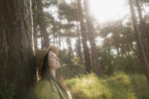 Woman relaxing against tree — Stock Photo