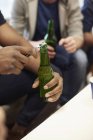 Ausgeschnittene Ansicht der Hände, die eine Flasche Bier öffnen — Stockfoto