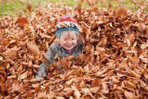 Mädchen spielt in den Blättern — Stockfoto