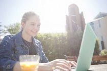 Teenage girl sitting outdoors using laptop computer, looking down smiling, Reykjavik, Iceland — Stock Photo