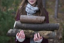 Giovane donna che raccoglie tronchi per falò nella foresta — Foto stock
